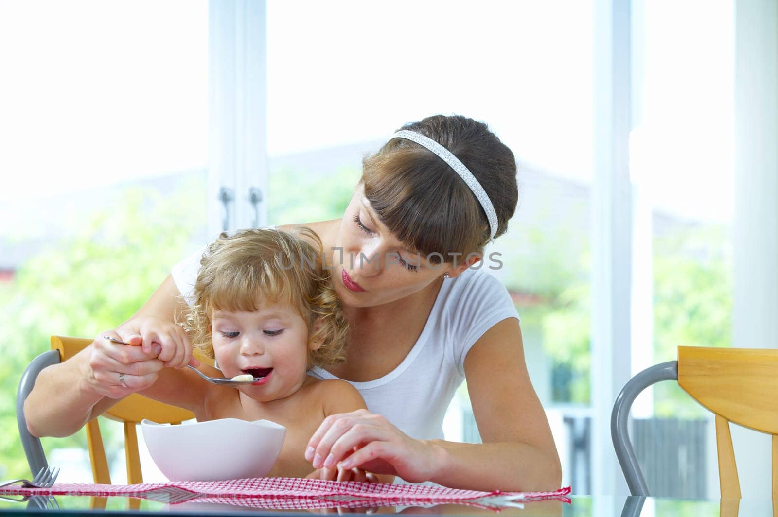 Portrait of young woman feeding her baby daughter