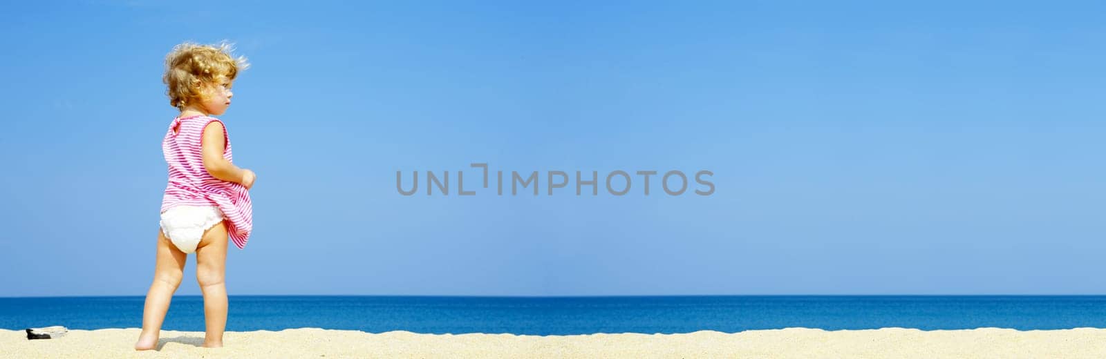 Portrait of blond blue eyed baby having fun on the beach. Banner lots of copy space