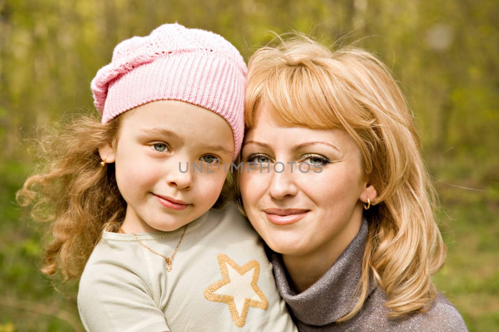 The beautiful little girl in a pink cap with smiling mum with light hair