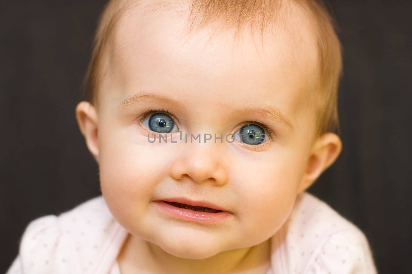 Close up of baby girl smiling on a black background