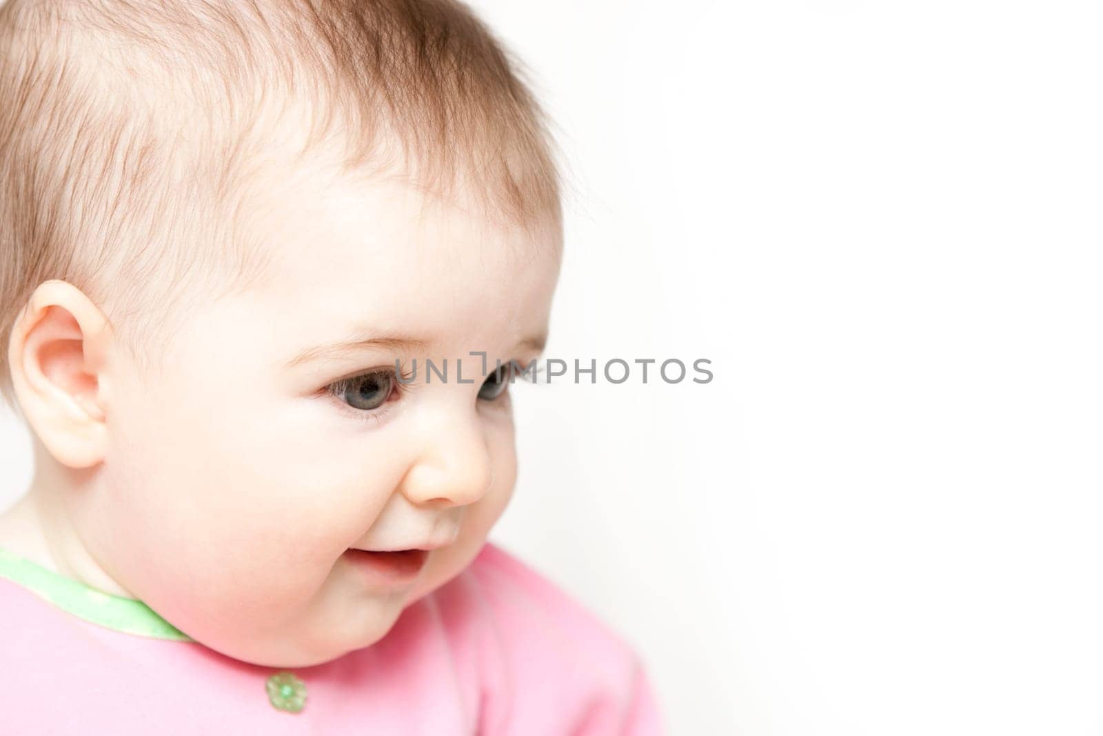 Sixth month old baby girl in pink and green clothes on white background with space for copy/text.