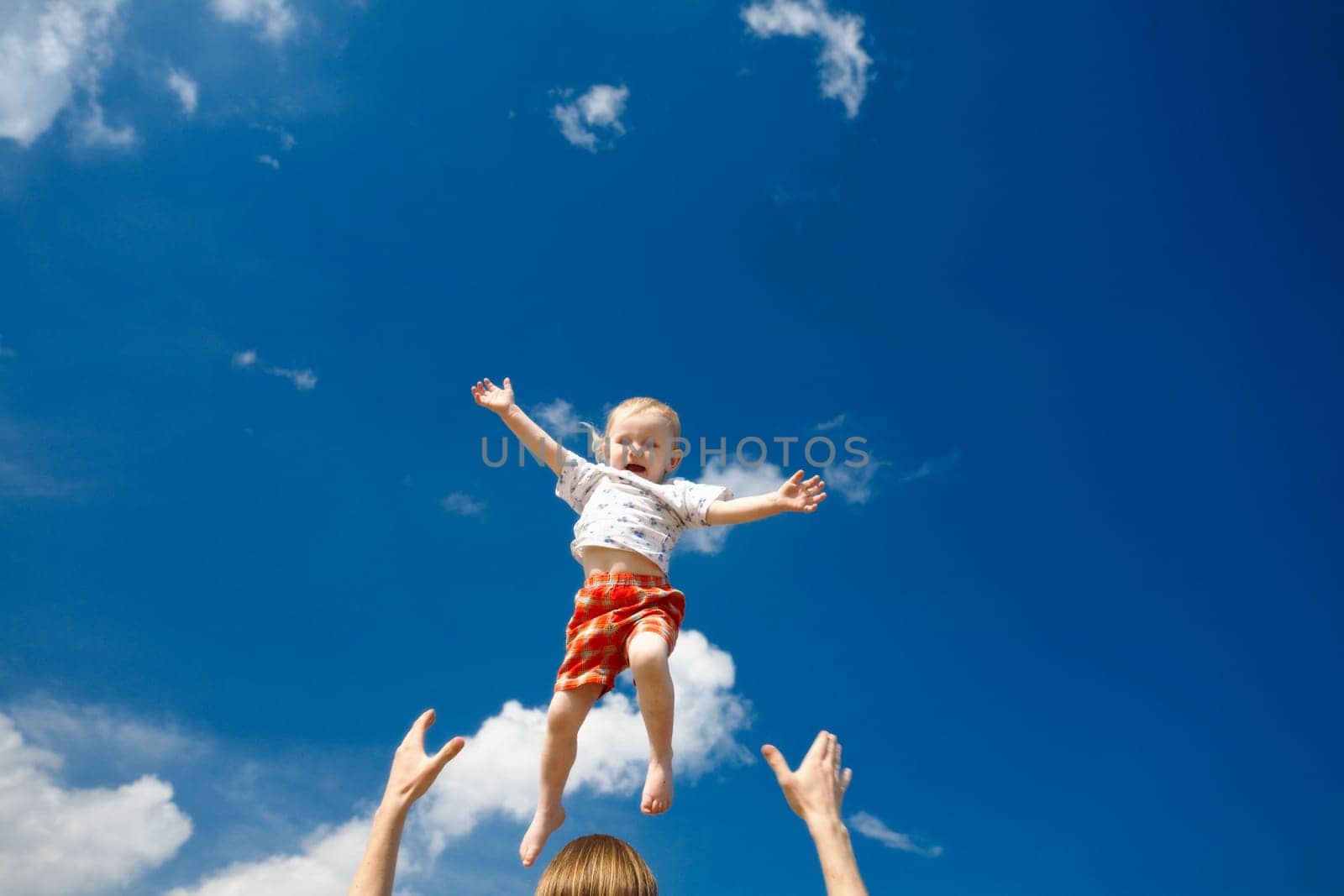 father throw his daughter over blue sky