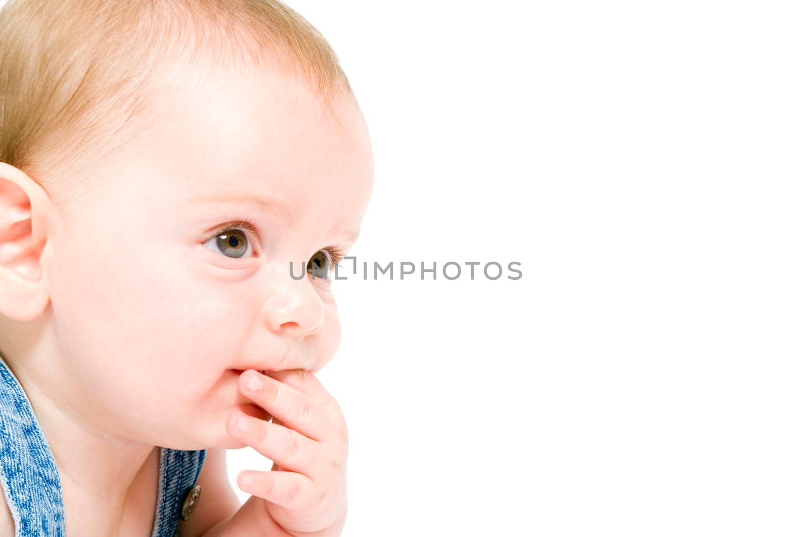 close-up of a six month old baby wearing jeans overall isolated on white