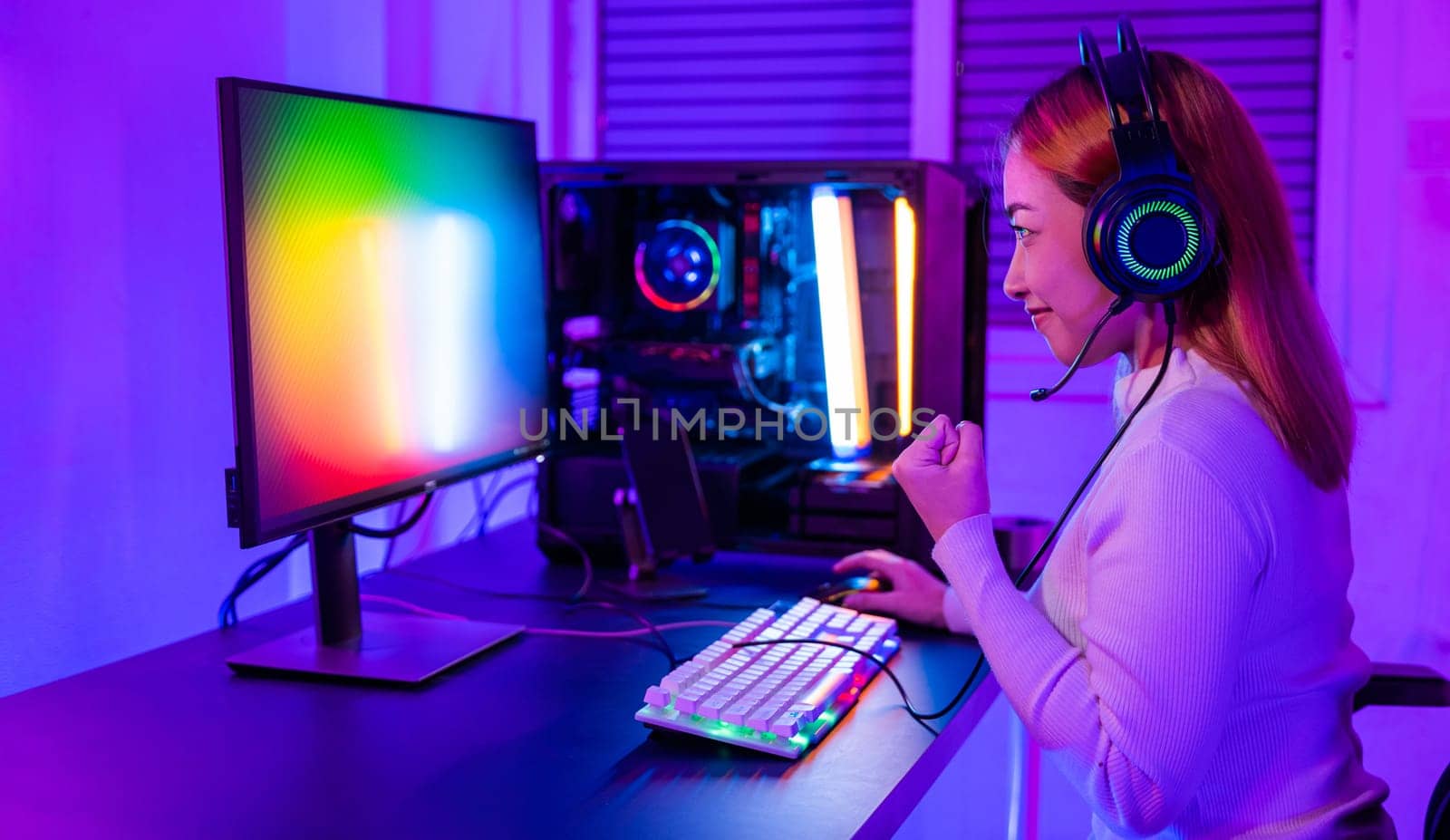 Winning Victory. Asian gamer playing online video game excited on desktop computer PC colorful neon LED lights, young woman in gaming headphones using computer she happy successful, E-Sport concept