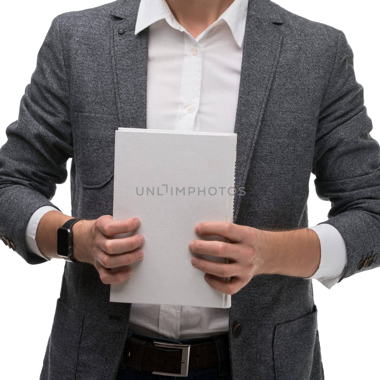 A man in a blazer stands holding blank sheets of paper in both hands, presenting a professional demeanor in a neutral setting.