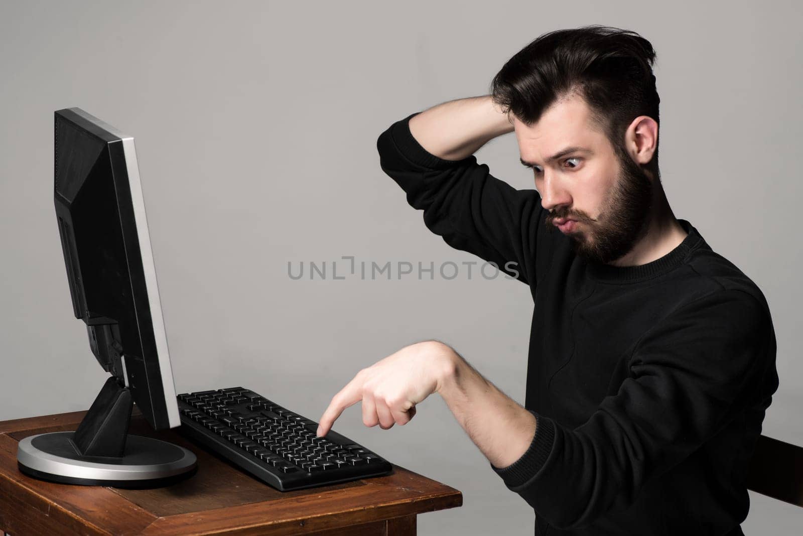 Funny and crazy man using a computer on gray background. man&#39 s hands on the keyboard