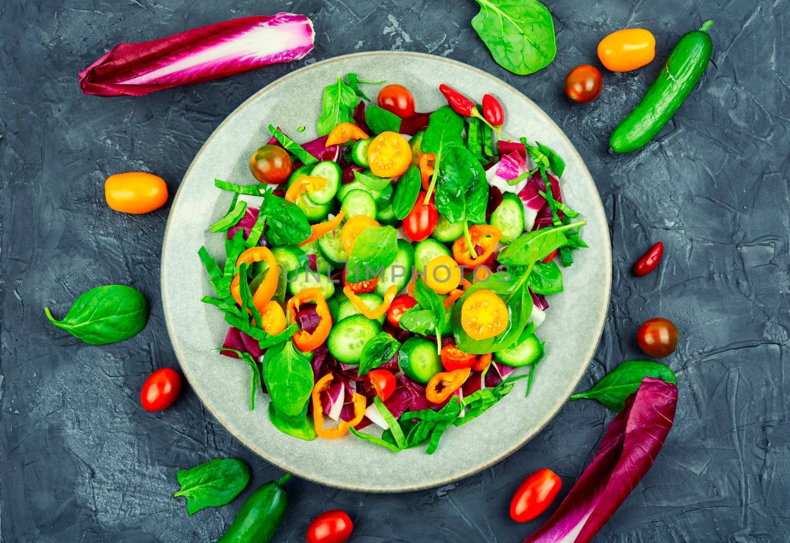 Summer delicious salad of tomatoes, cucumbers, peppers and spinach.