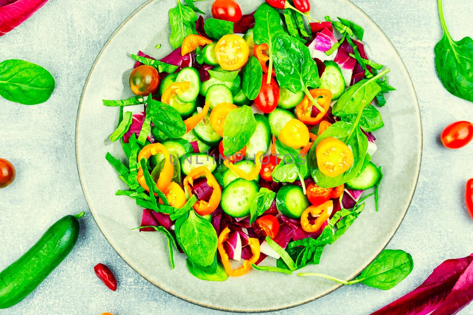 Summer delicious salad of tomatoes, cucumbers, peppers and spinach.