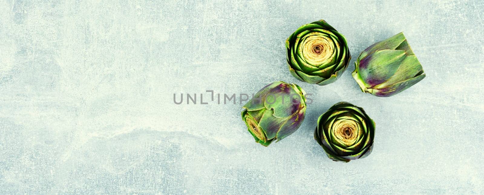 Unopened raw artichoke buds, food on kitchen table. Italian cuisine
