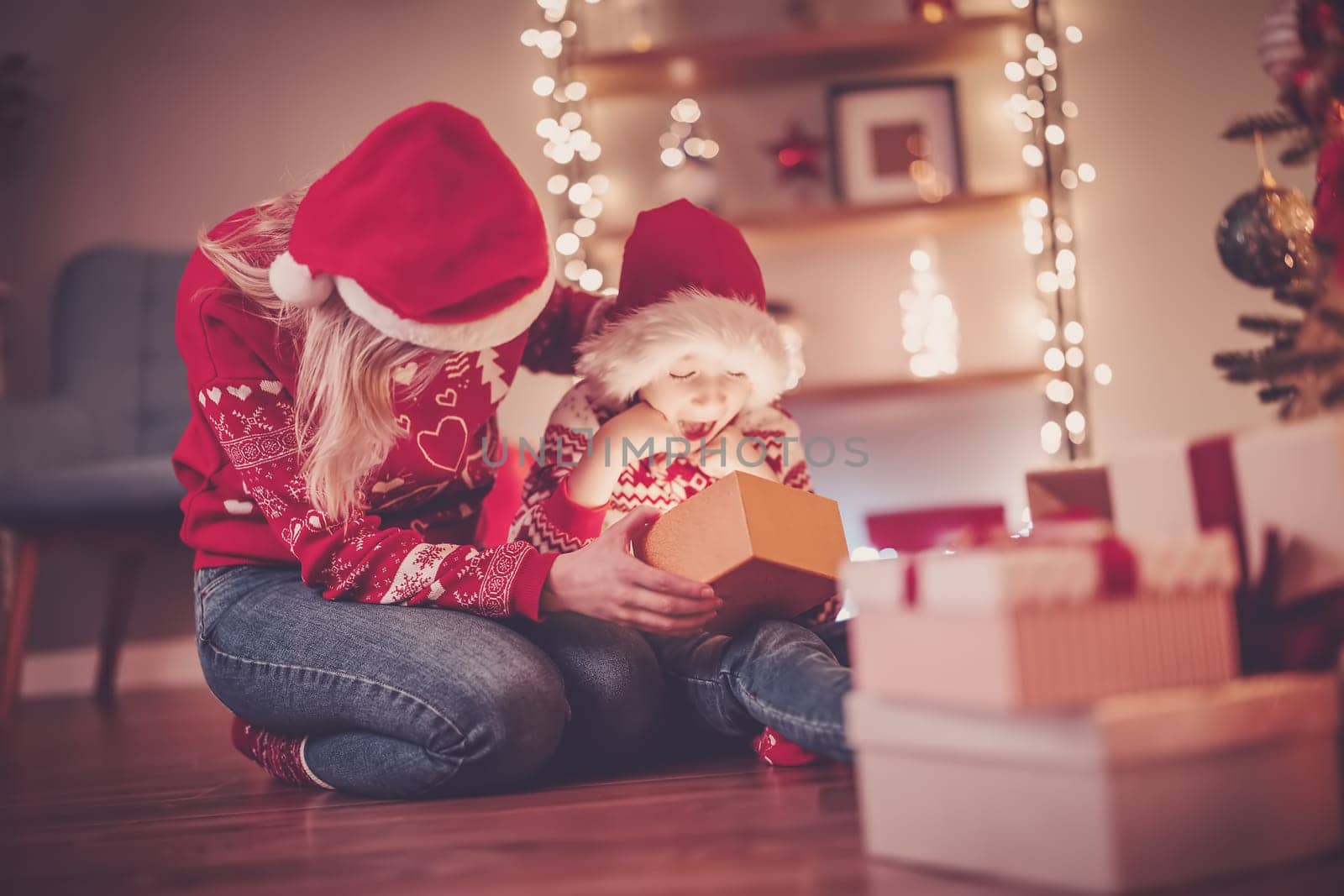 Mother and son indoors looking inside of gift box in Christmas eve. Concept of Christmastime and New Year.