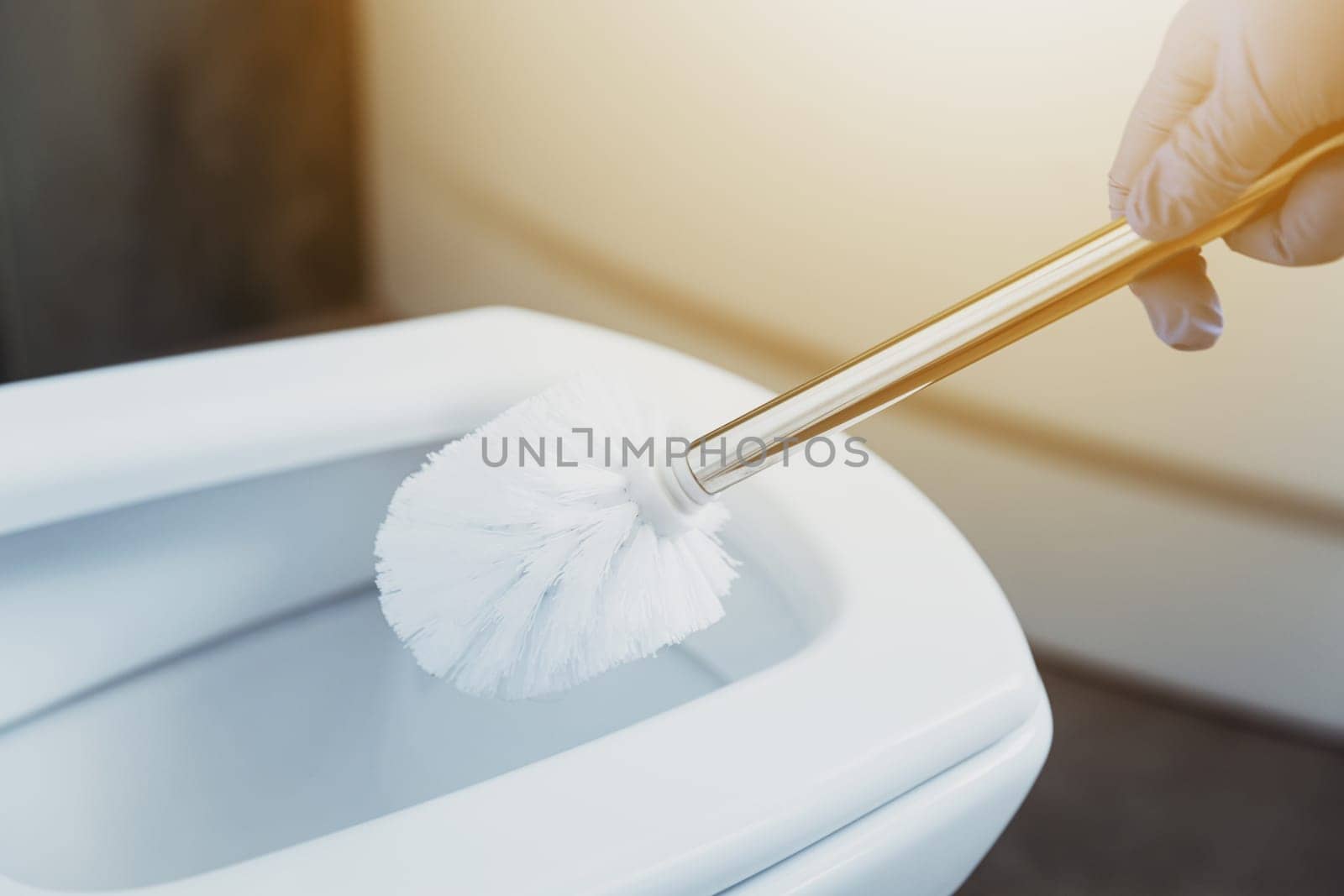 Close up on housewife hands in gloves cleaning toilet bowl with scrub brush in bathroom or public restroom. Disinfection, hygiene, cleaning service concept. Female washing, disinfecting toilet seat.