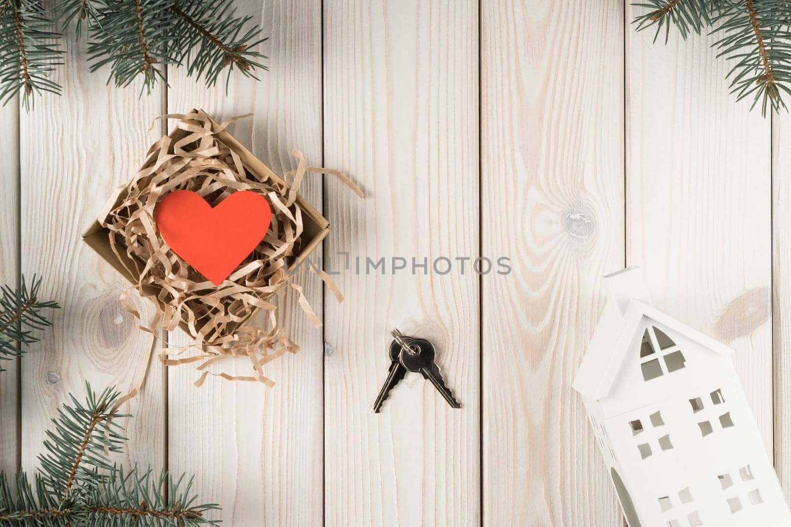 Open wrapping paper box with red heart present and metallic key with house model in pine tee twigs decoration on wooden view. Moving apartment, mortgage, lucky purchase. Flat lay, top view, copy space