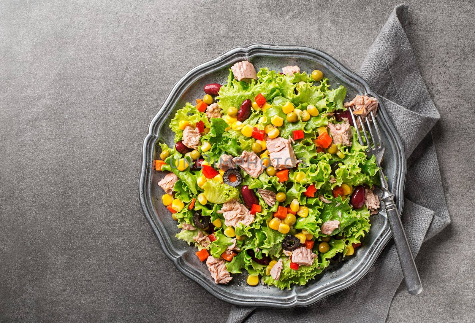 Healthy Green salad with tuna and vegetable on grey table background. Mexican corn salad.