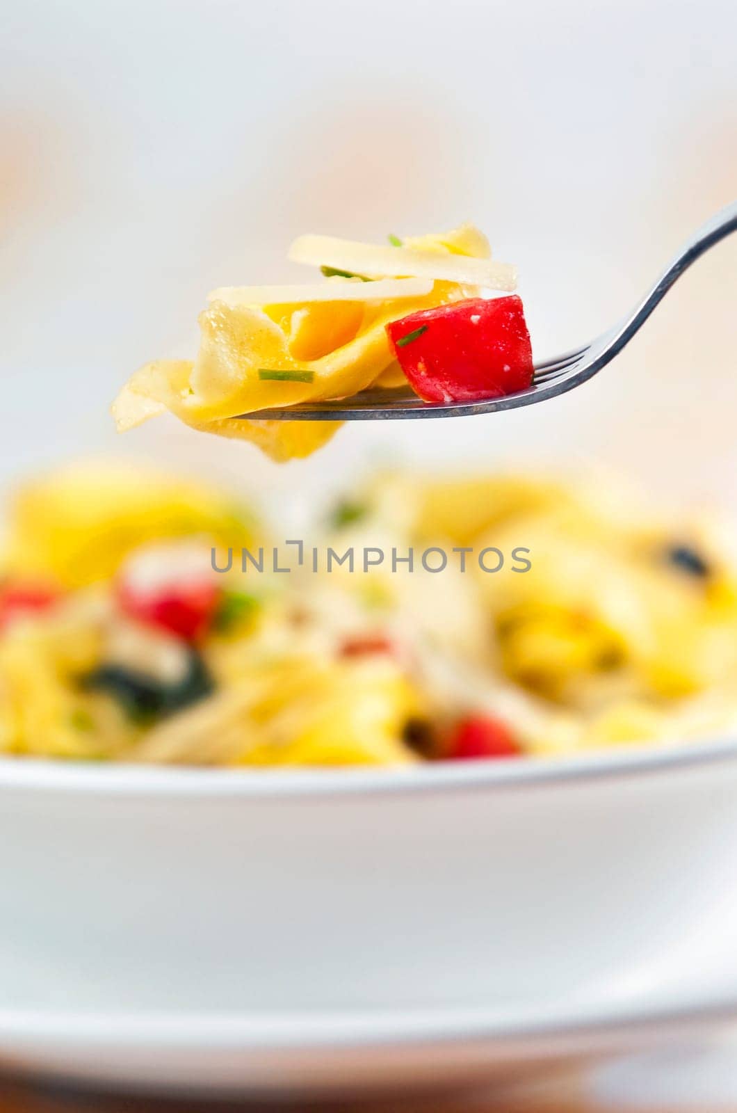 Tortellini primavera garnished with basil leaves on white plate