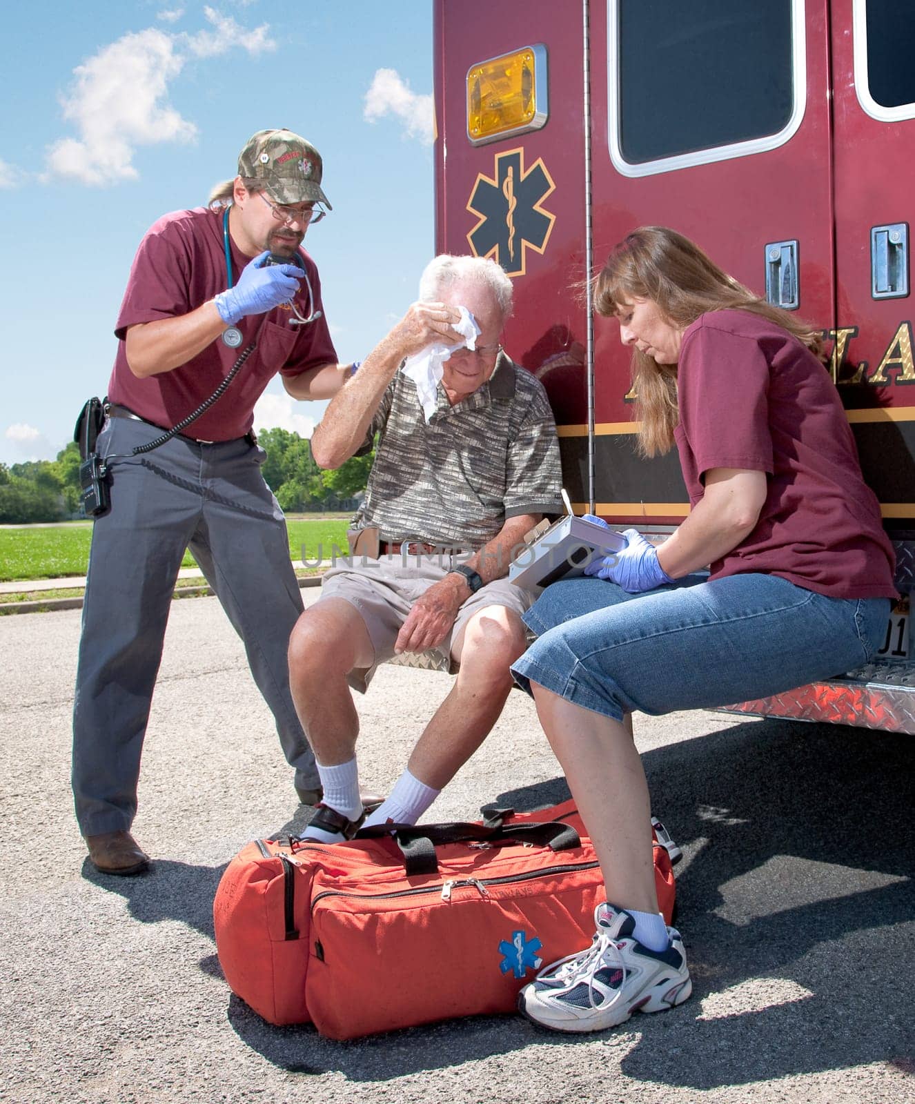 Two EMTs review a patients injuries while sitting on the back step of the ambulance