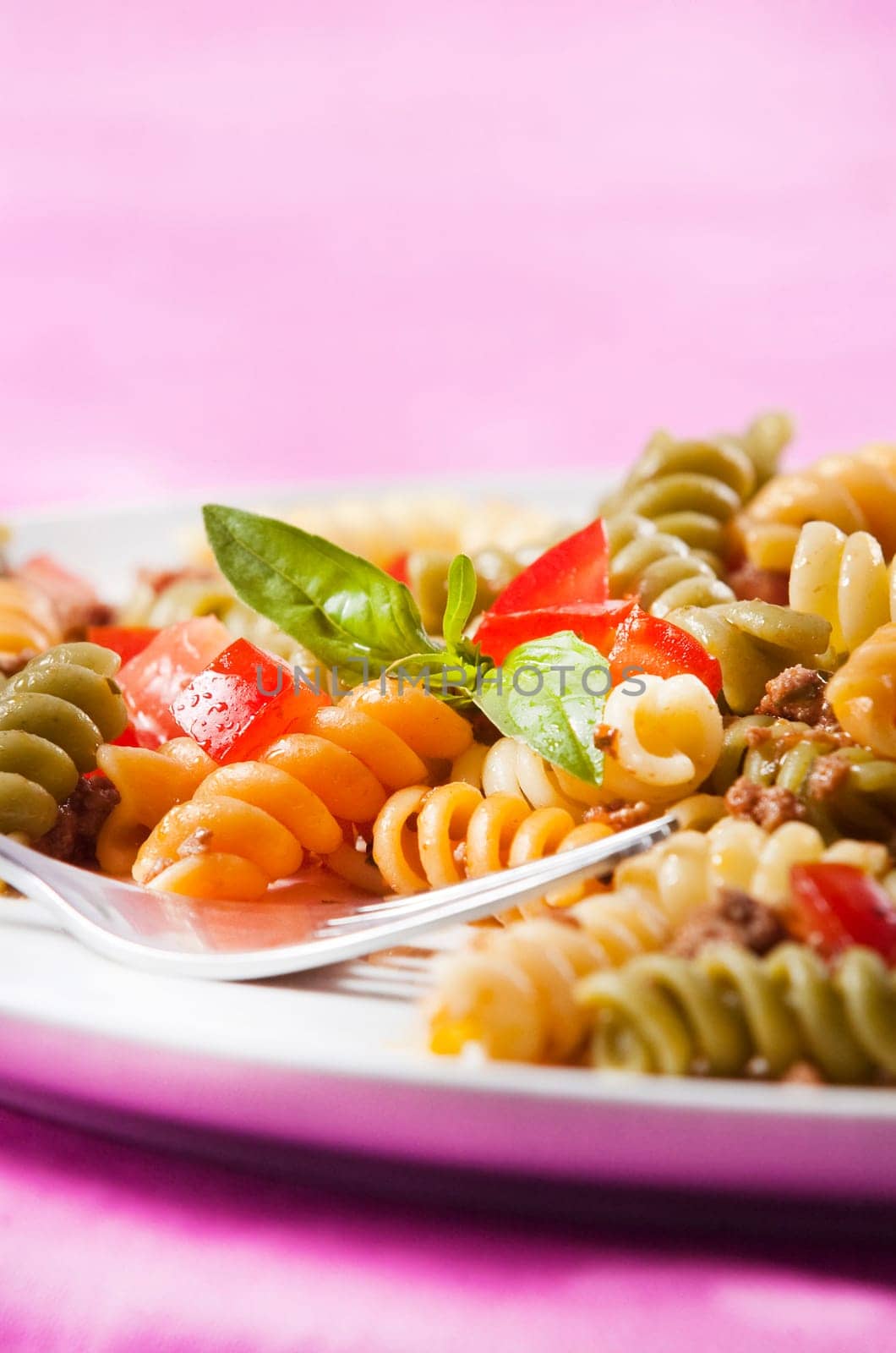 Pasta primavera garnished with basil leaves