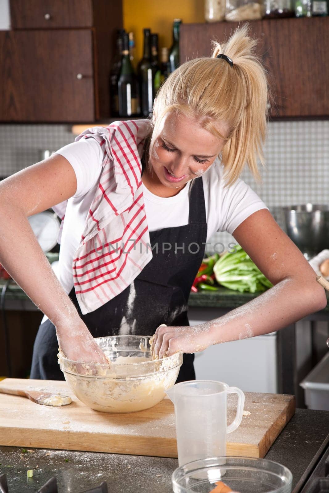 Female chef getting flour all over her self while kneading the dough