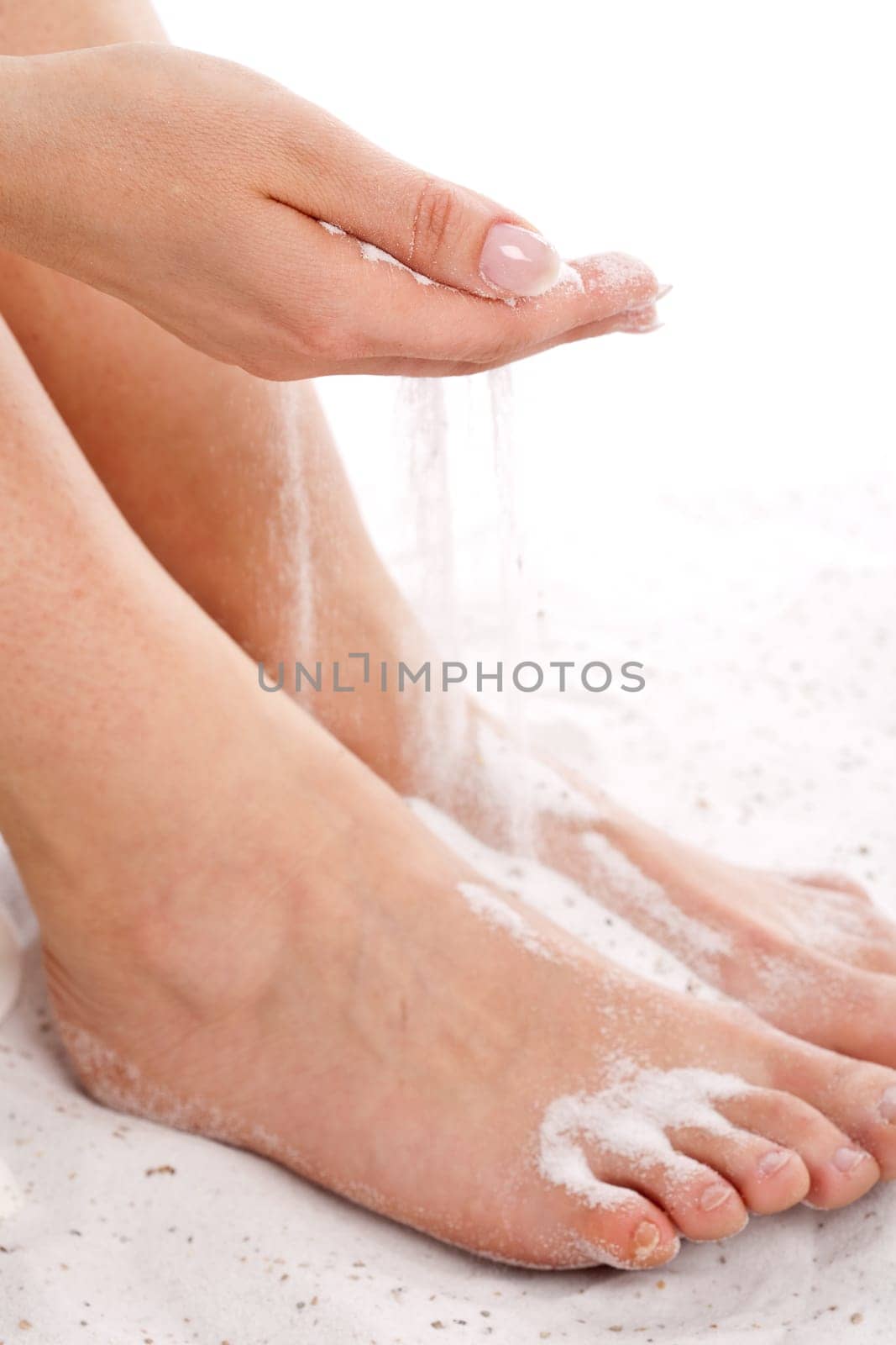 Hand running the sand through her fingers on her bare feet (focus on hands)