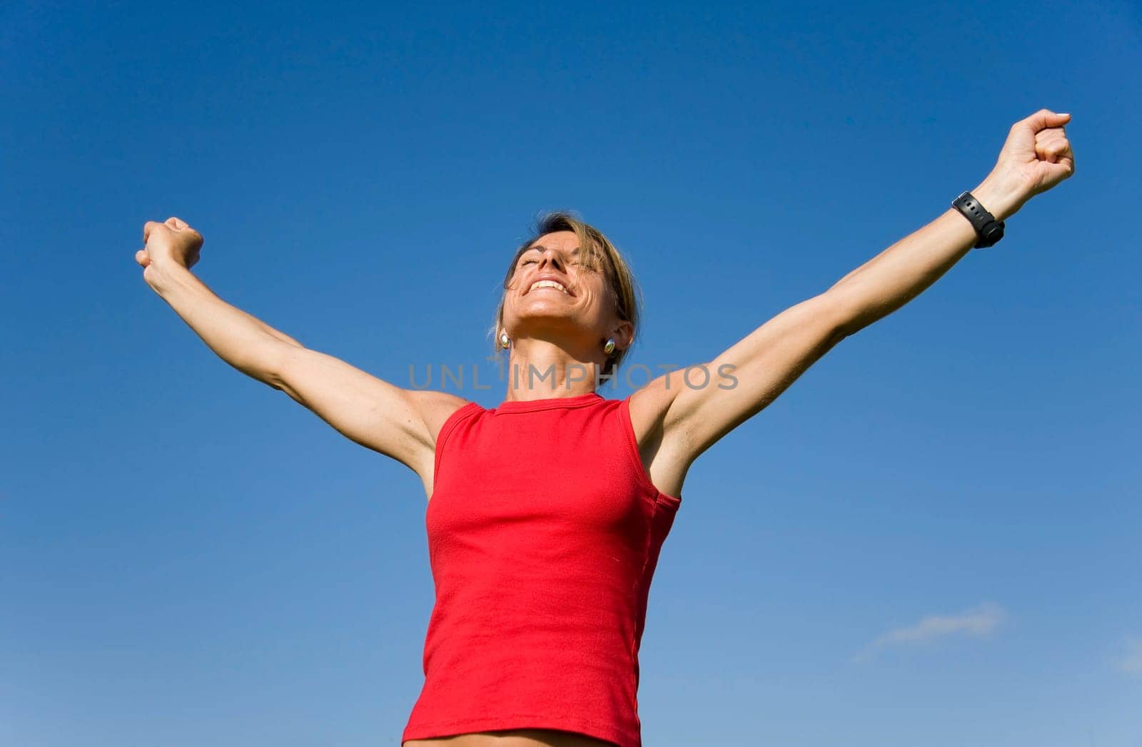 Beautiful women with her arms outstretched on a blue sky