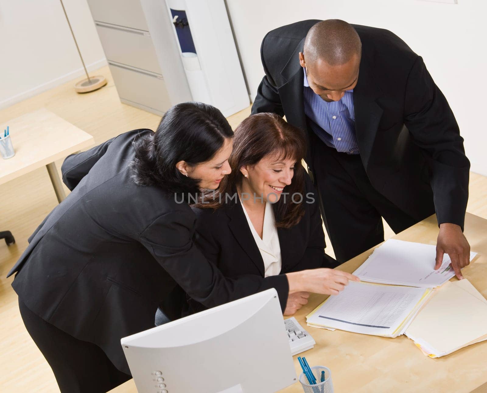 A group of business people are working together in an office. They are looking at paperwork.  Horizontally framed shot.