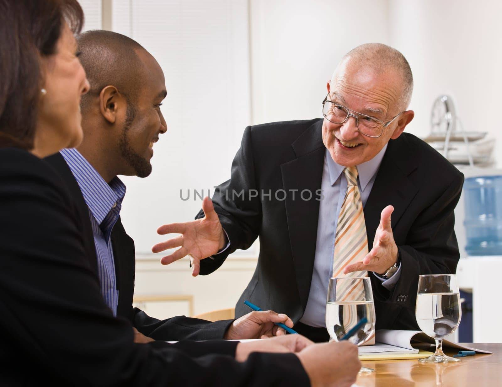 Business team meeting with two men and a woman sitting at a desk with water.  Horizontal