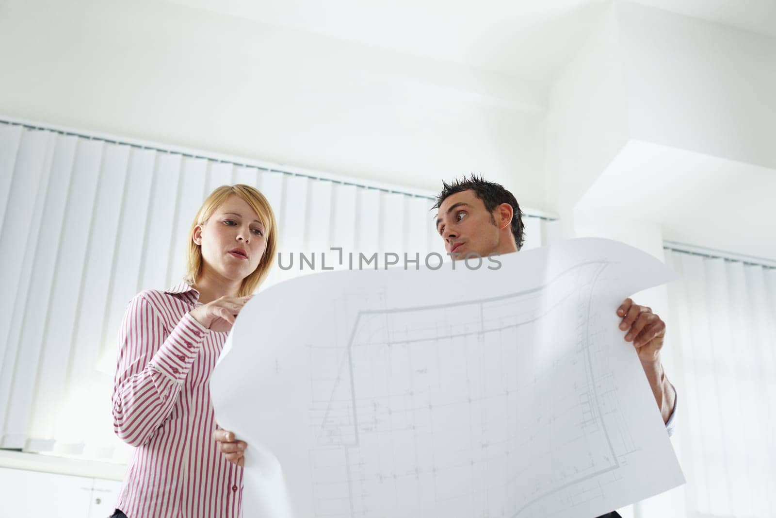 two architects examining blueprint indoors. Low angle view. Copy space