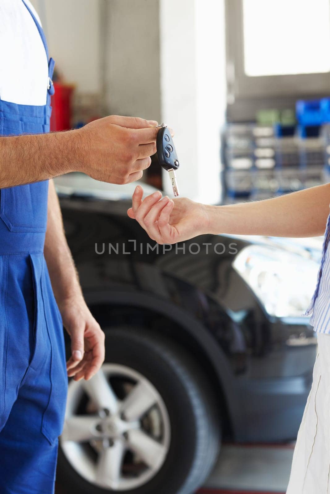 cropped view of mechanic giving car keys to female client