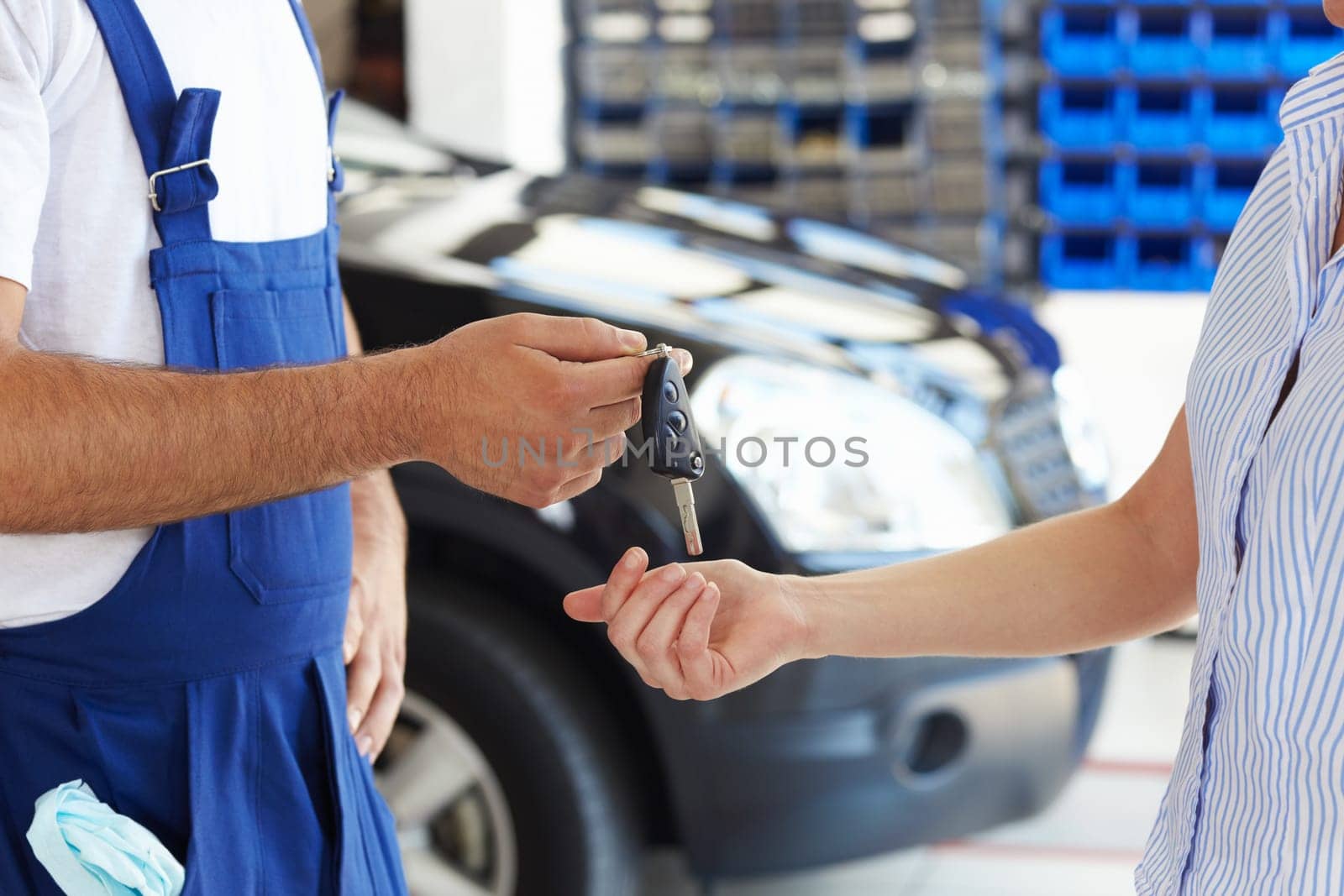 cropped view of mechanic giving car keys to female client