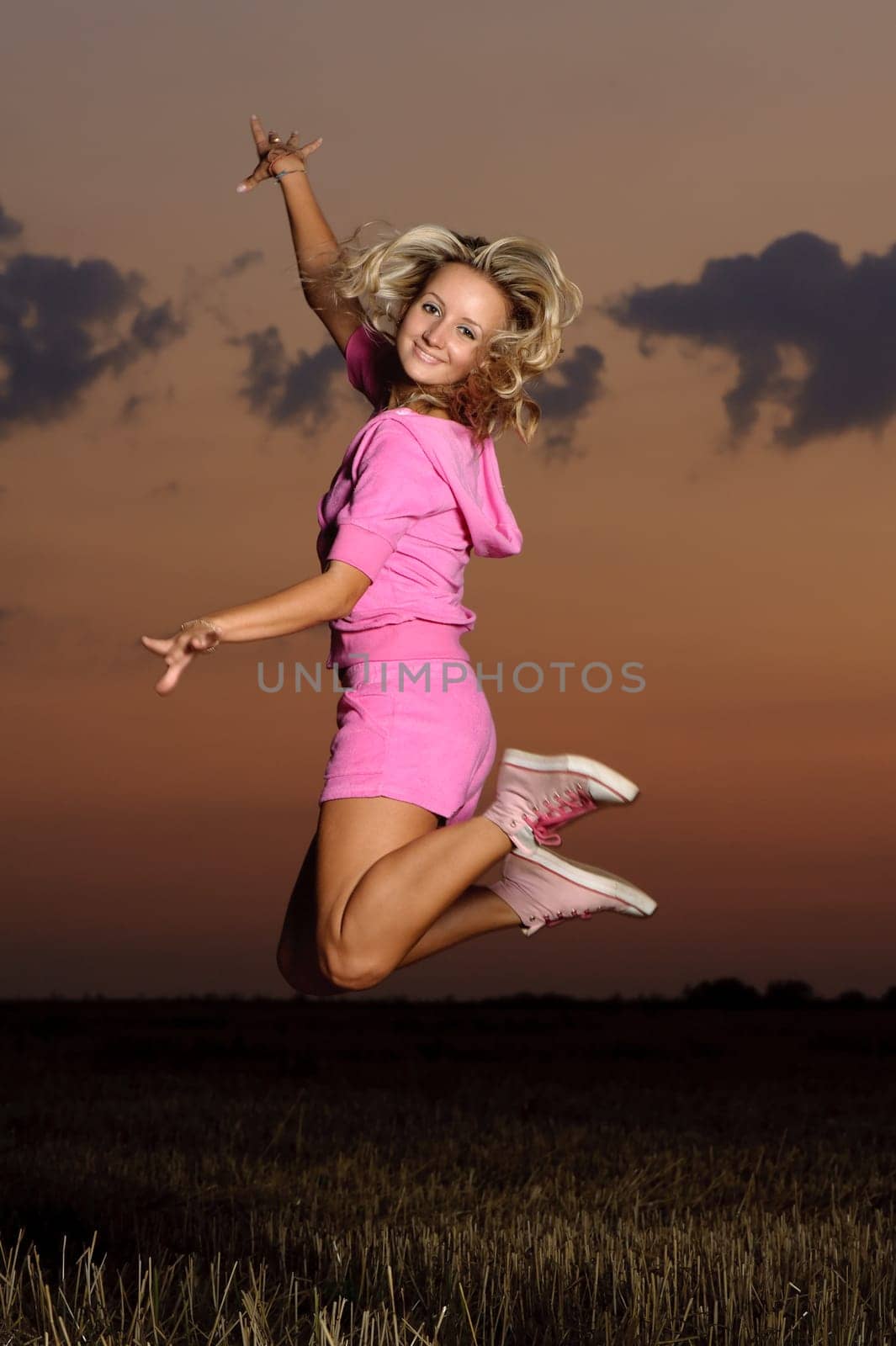 blond girl outdoor jumping at evening time