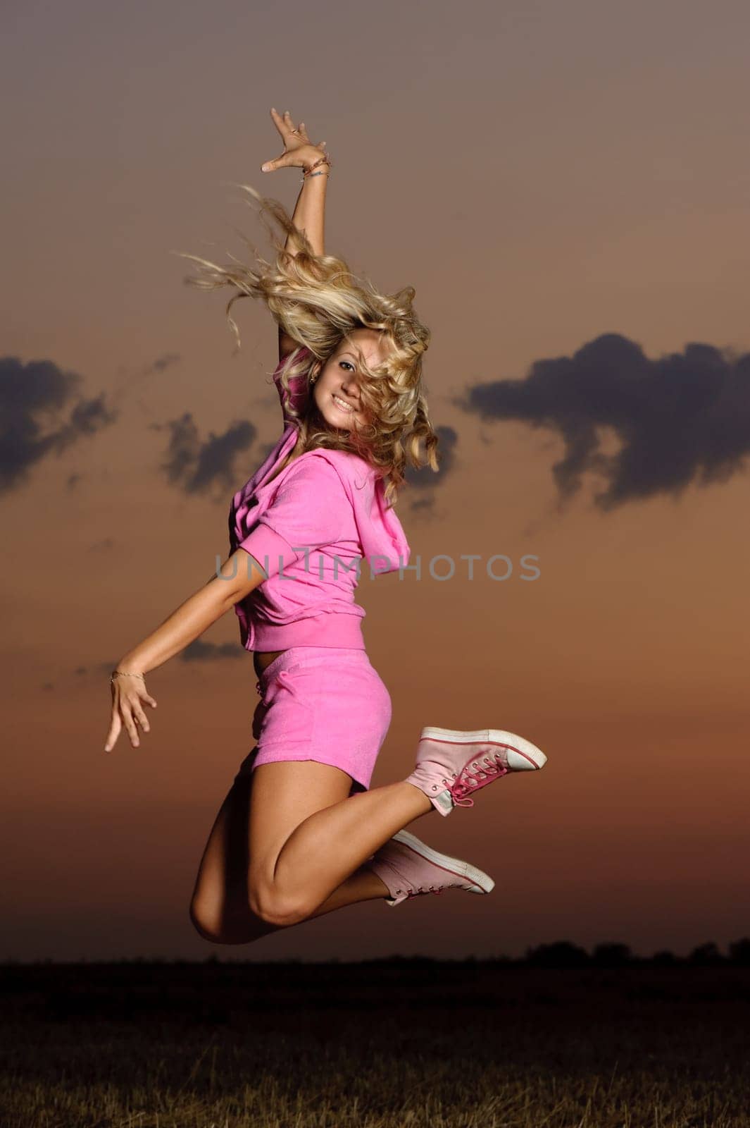 blond girl outdoor jumping at evening time