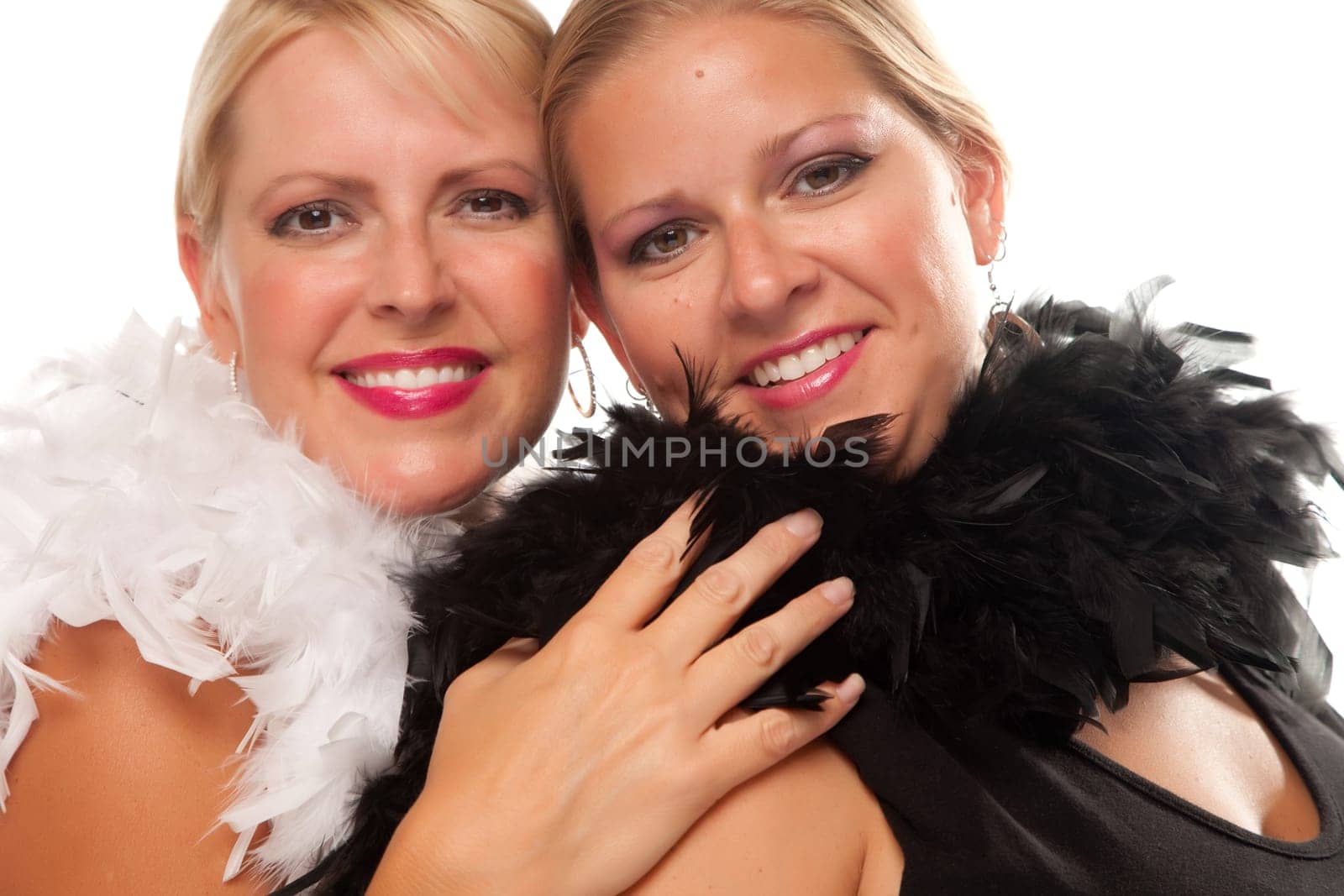 Portrait of Two Blonde Haired Smiling Girls with Feather Boas Isolated on a White Background.