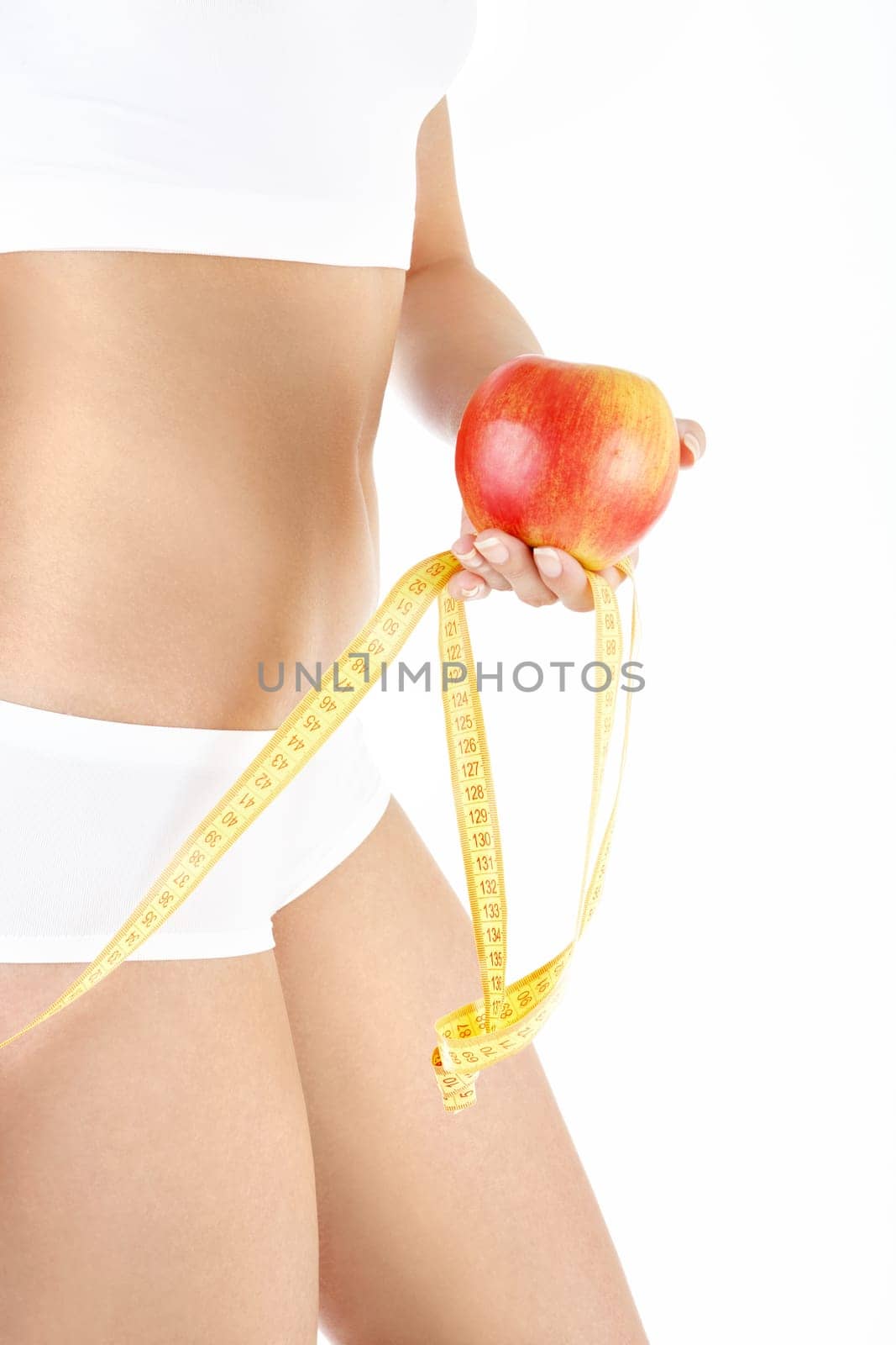 Close up sideways a female stomach, the hand holds an apple, isolated