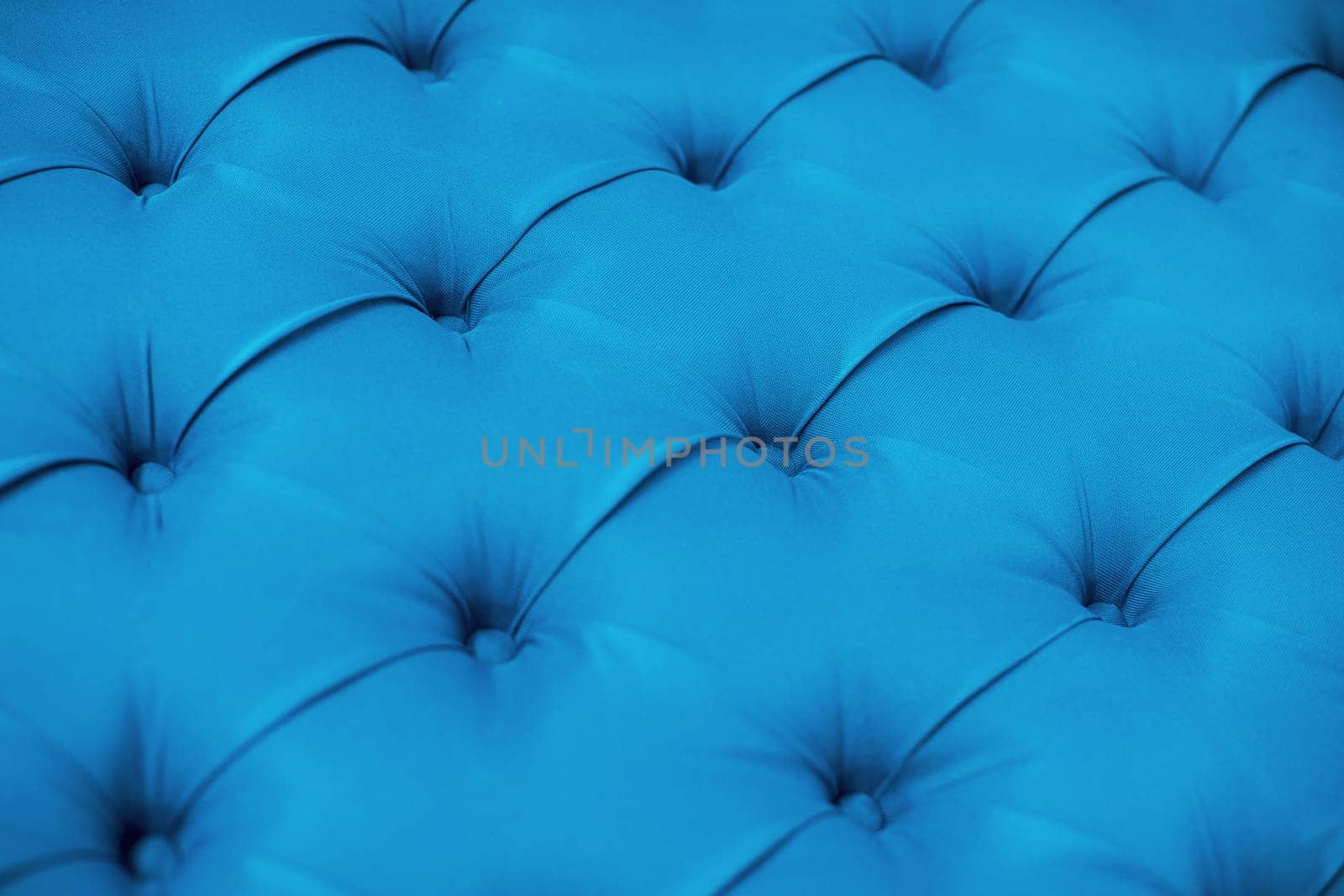 Blue upholstered furniture from fabric texture. Ement quilted sofa. Interior design, headboards made of furniture fabric upholstery. Classic checkered pattern background for furniture, wall, headboard