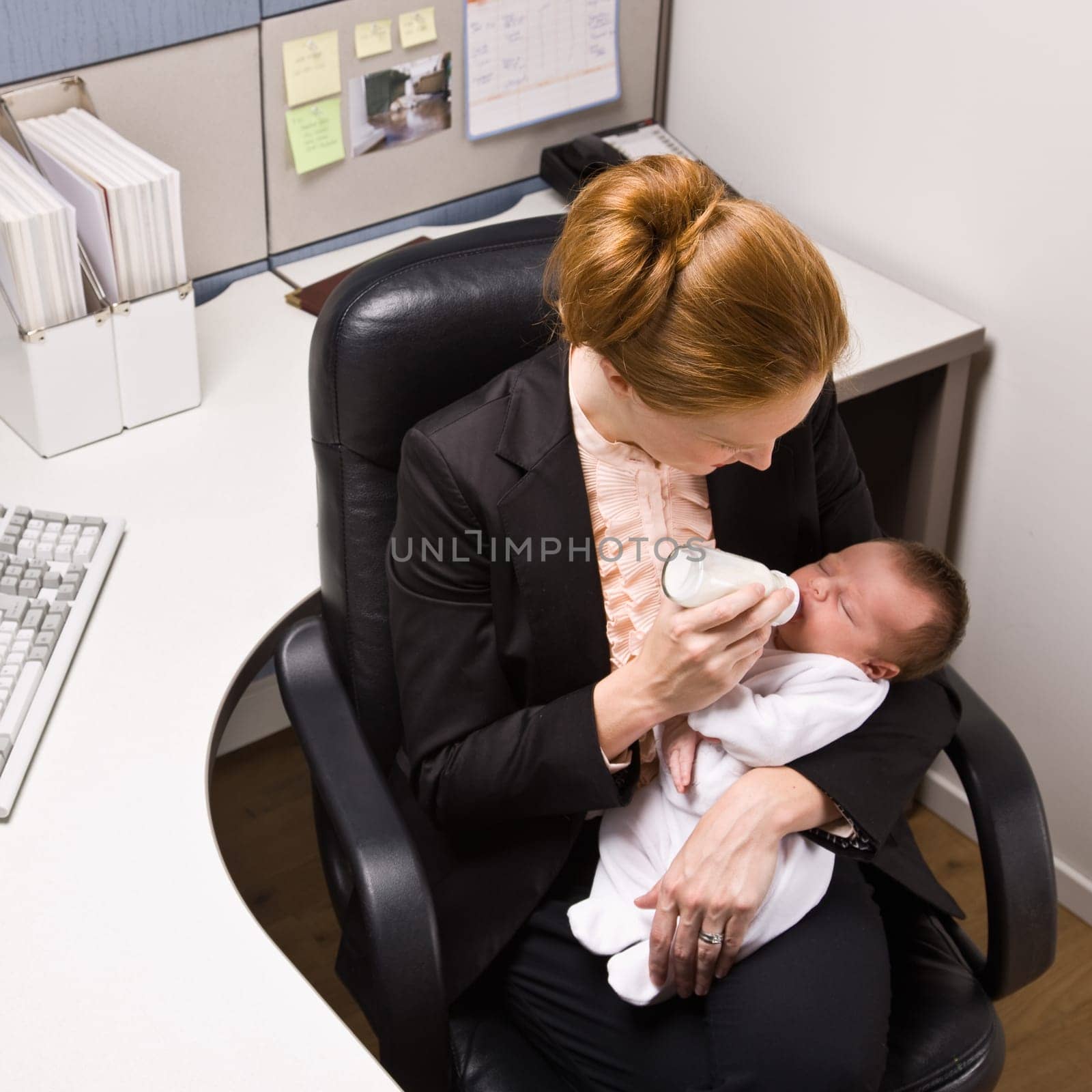 Businesswoman feeding baby at desk
