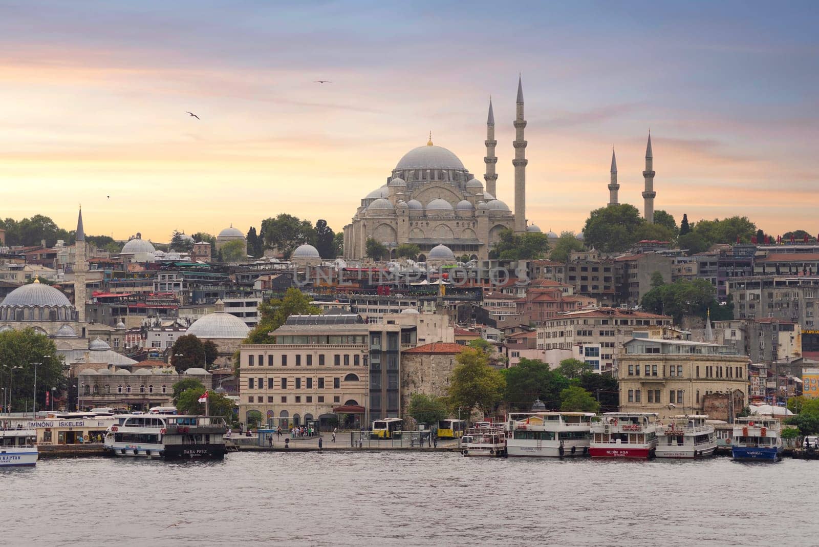 Istanbul, Turkey - August 25, 2022: Istanbul city view from Galata Bridge at Eminonu overlooking the Golden Horn with ferries, ferry terminals, and Suleymaniye Mosque before sunset