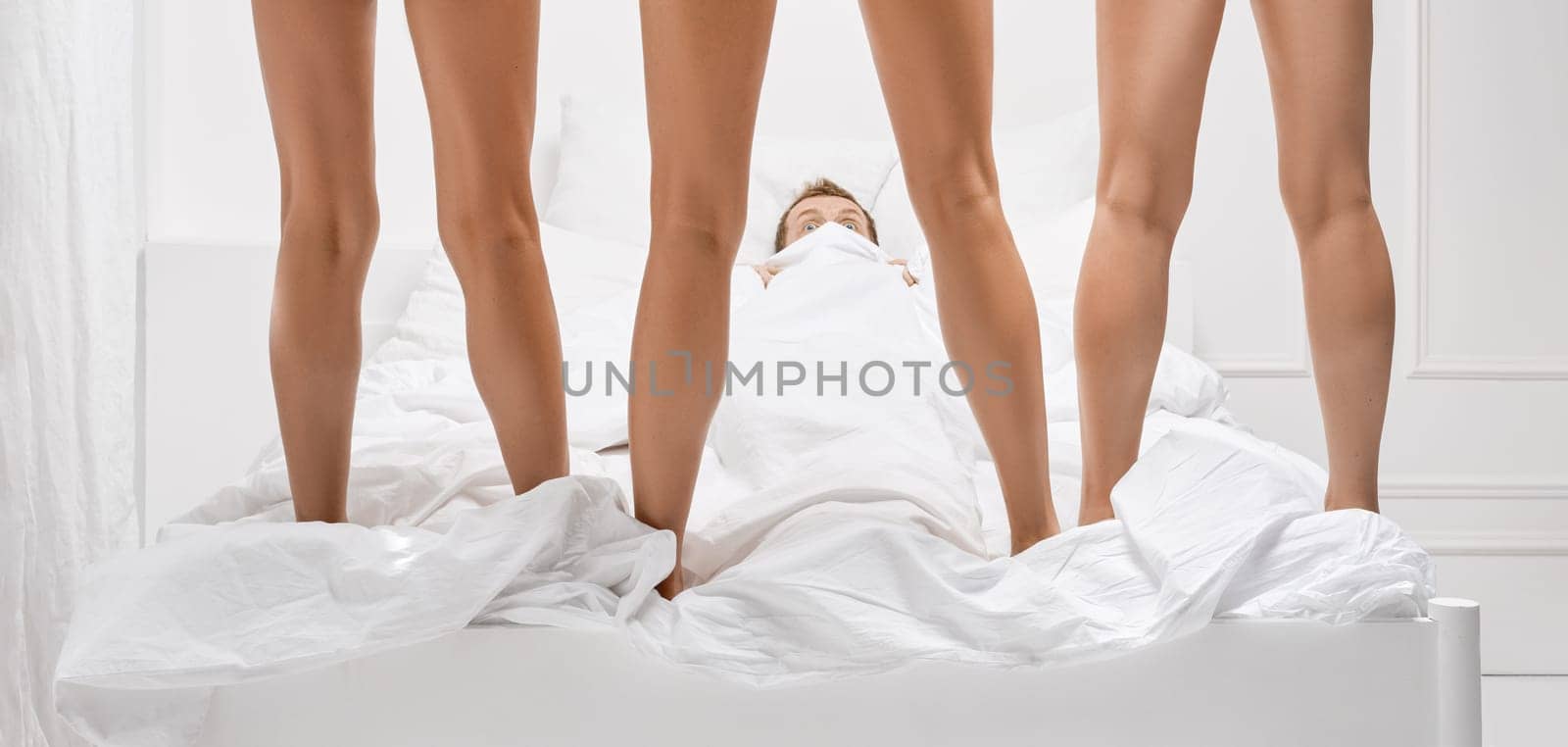 Male fears and sexual problems in bed.  Scared man hides from three women in bed
