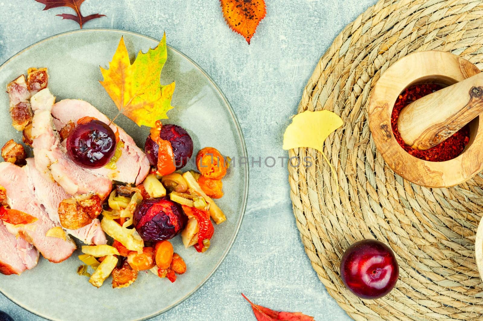 Juicy pork shoulder with skin and bacon cooked with vegetables and plums.