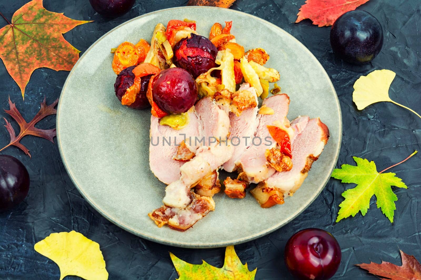Juicy pork shoulder with skin and bacon cooked with vegetables and plums.
