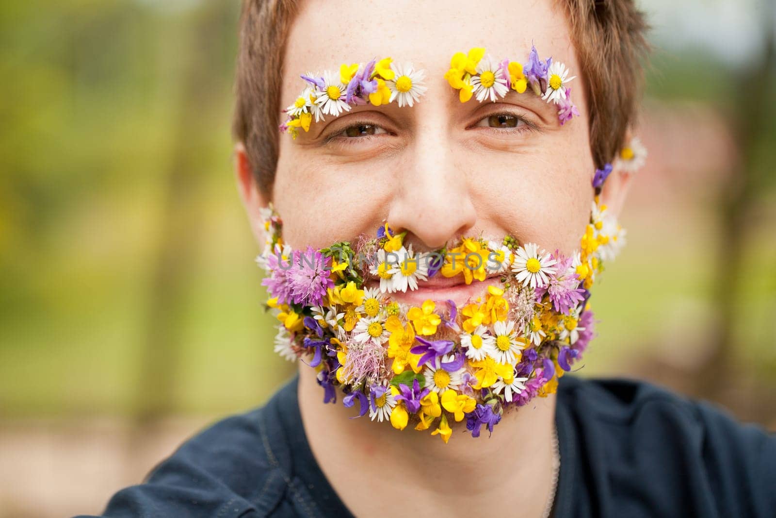 happy hipster man in the nature with flower beard and eyebrows smiling