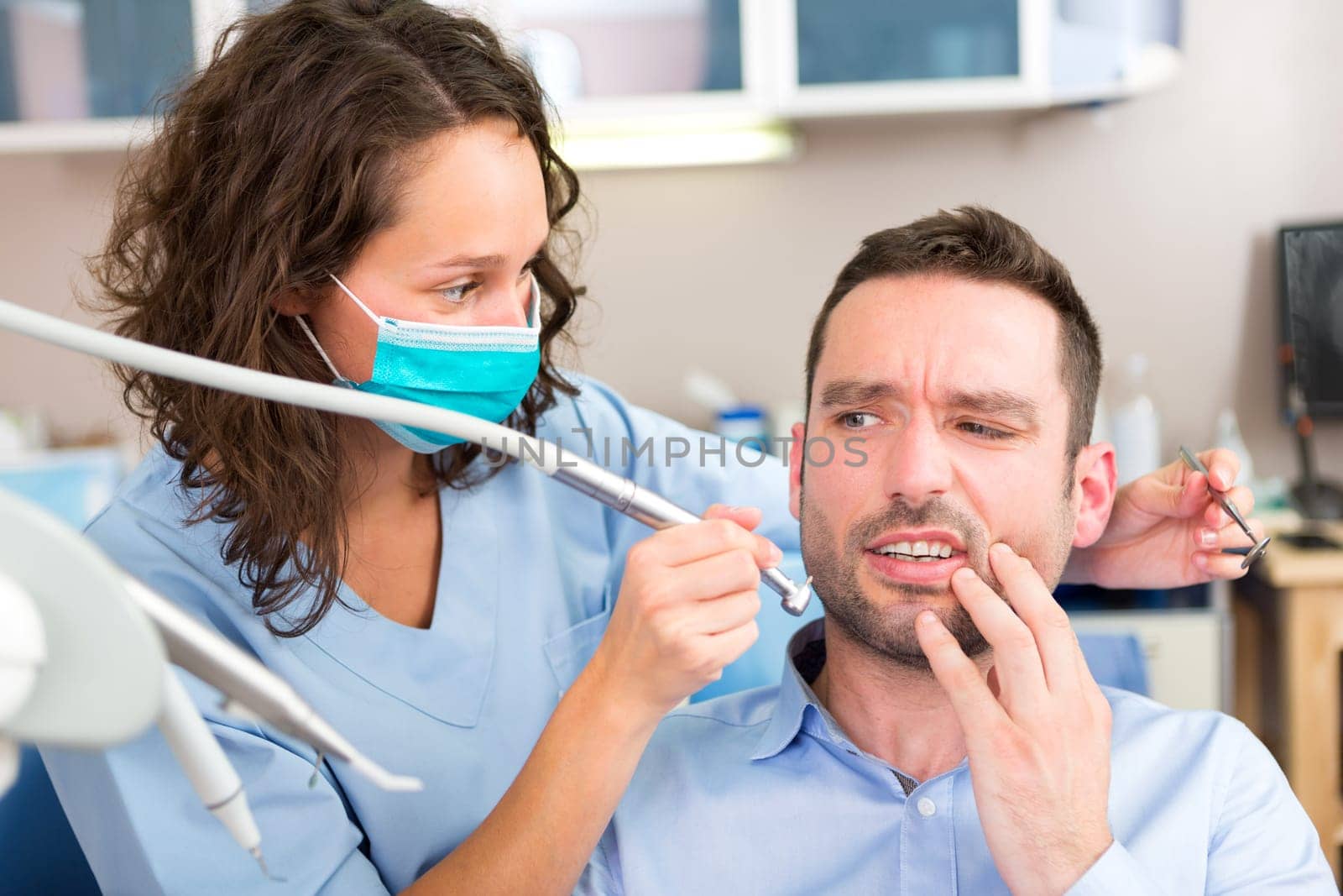 View of a Young attractive man scared to being cured by a dentist