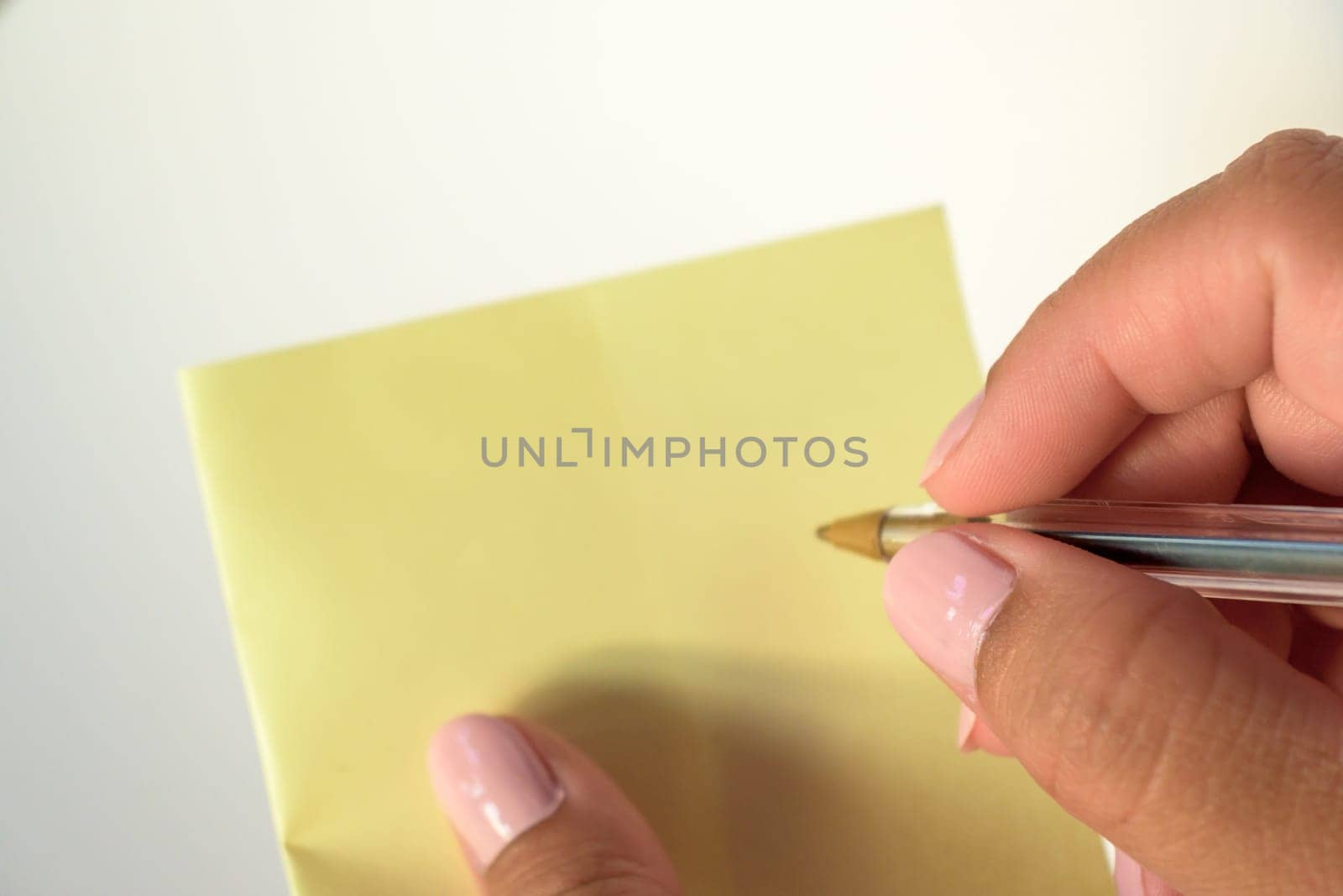 Woman's hand with painted nails holding blank letter paper on pure white background.