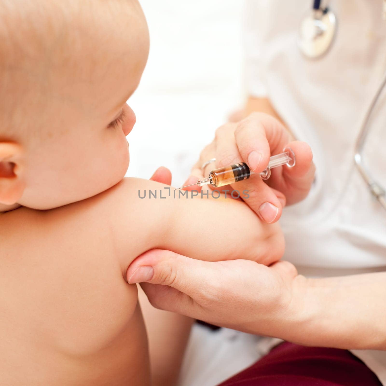 Doctor giving a child an intramuscular injection in arm, shallow DOF
