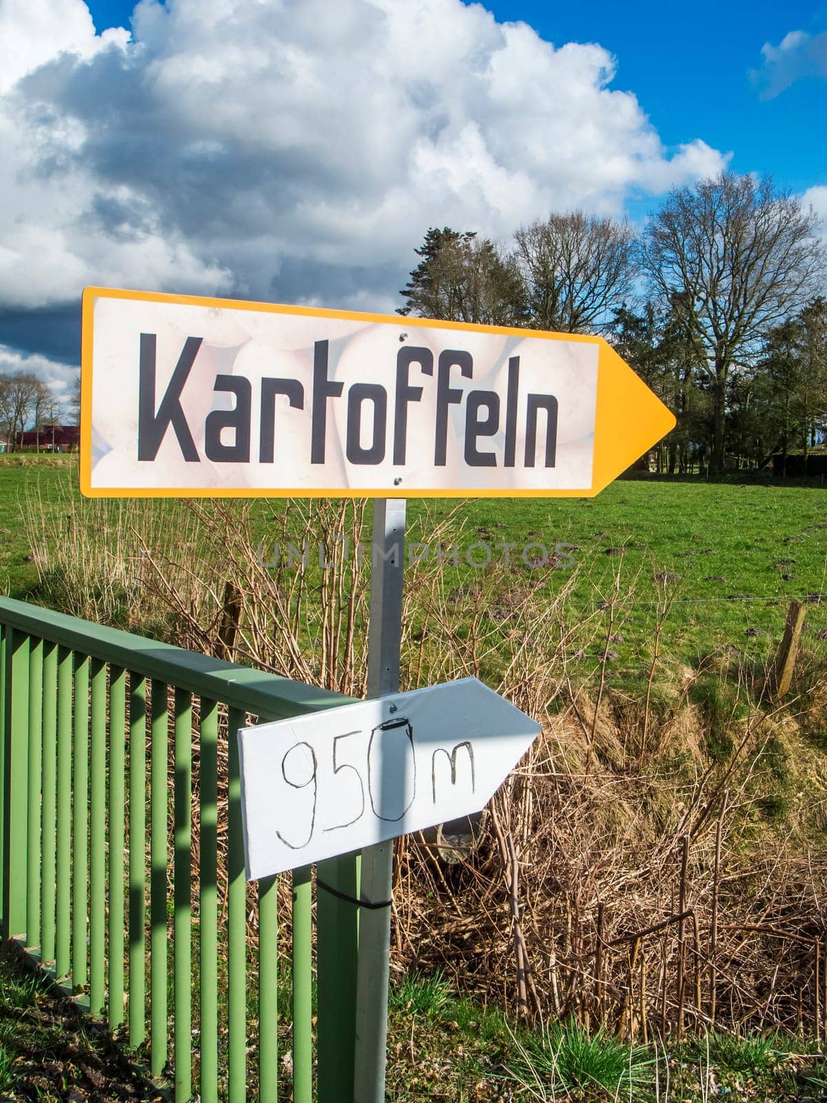 Information sign for direct potato sales on a country road in East Friesland with a blue sky and large white clouds.