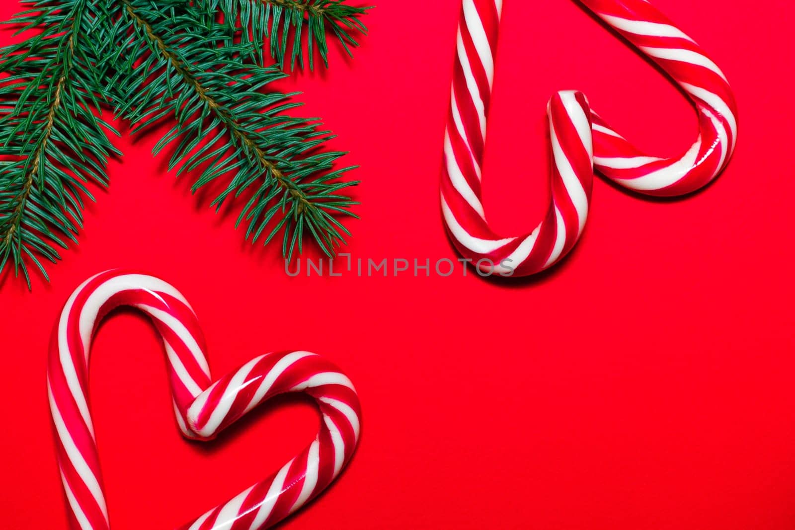 Lollipop hearts on red surface with Christmas tree branches. Christmas and New Year greeting card