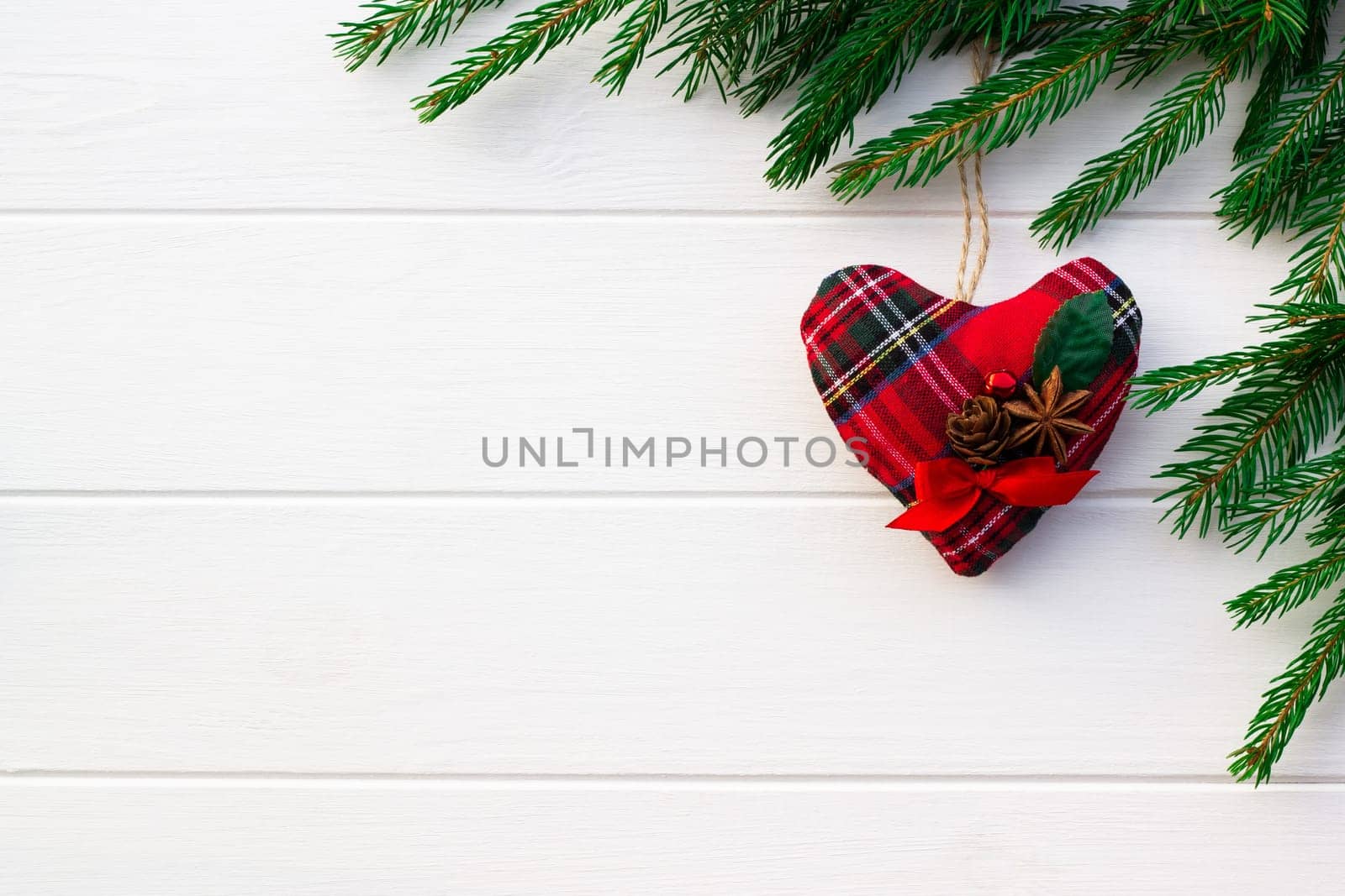 Green branches of a Christmas tree with DIY soft decoration on a background of white boards. Flat lay, copy space.