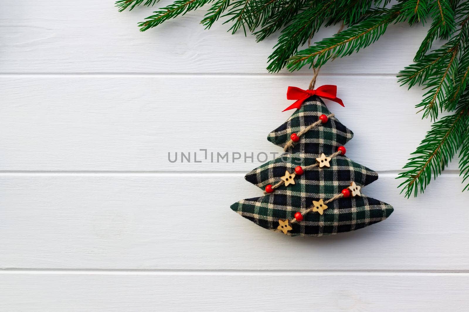Green branches of a Christmas tree with DIY soft decoration on a background of white boards. Flat lay, copy space.