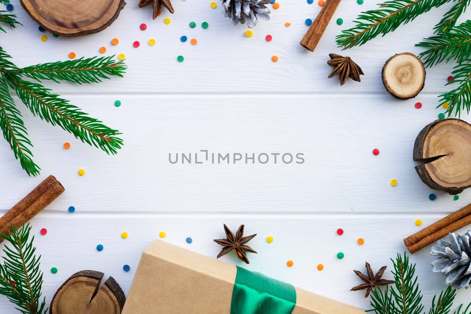 Green branches of a Christmas tree and confetti on a background of white boards. Flat lay. Copy space