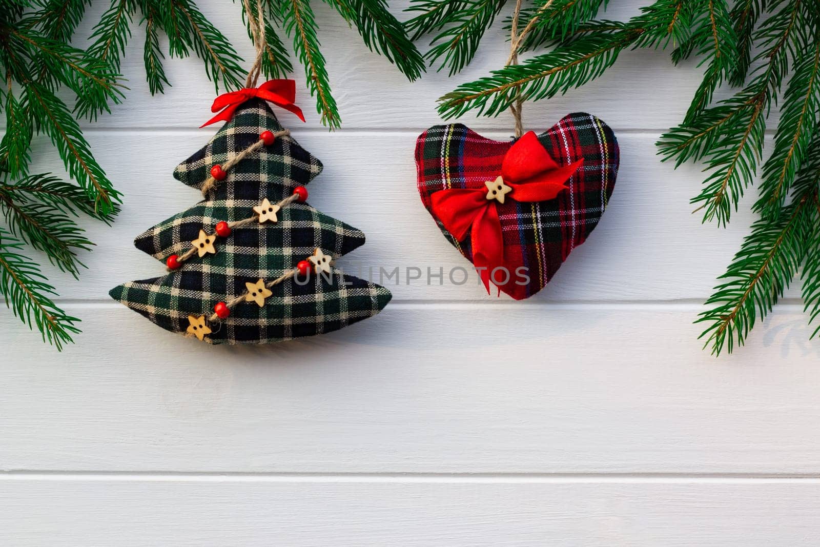 Green branches of a Christmas tree with DIY soft decoration on a background of white boards. Flat lay, copy space.