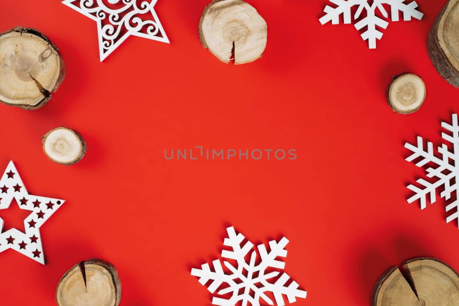 Wood cuts or branch slabs and wooden snowflakes on red background. Christmas or New Year concept. Flat lay. Copy space