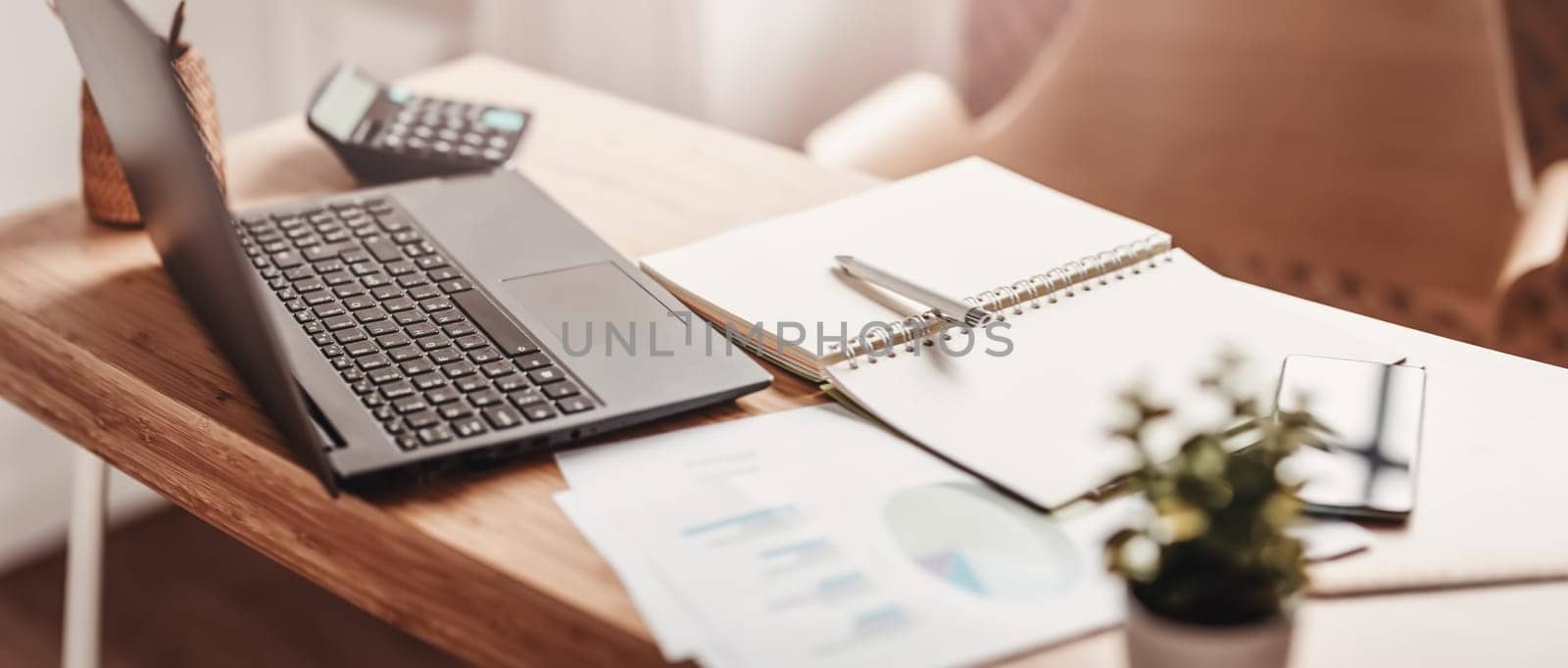 Close-up panoramic view of the table with laptop and papers on it in the office. Concept of the workplace.